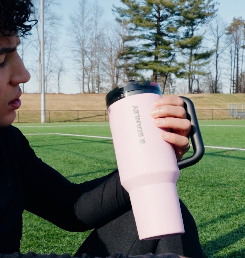Soccer field campaign holding a pink Stanley tumbler
